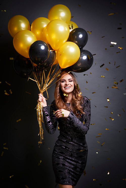 Shot of smiley woman holding bunch of balloons