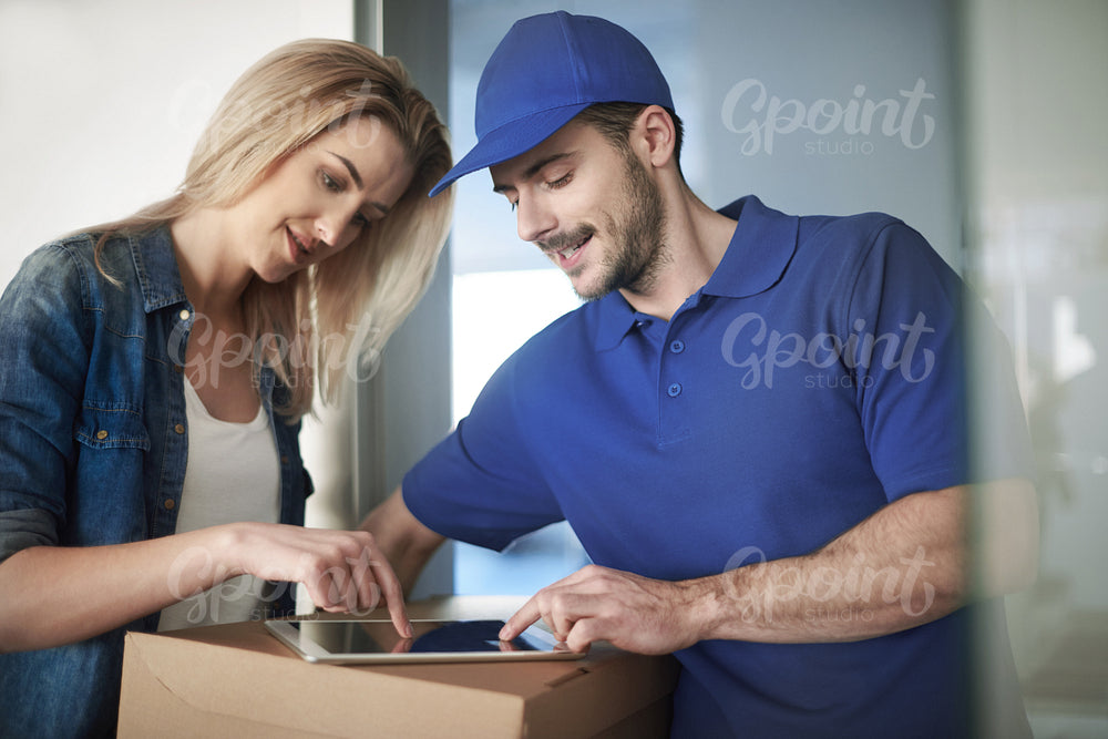 Woman signing package by using digital tablet