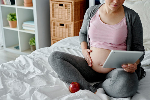 Pregnant woman checking something on the tablet