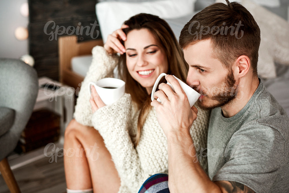Cheerful man and woman drinking coffee in bedroom