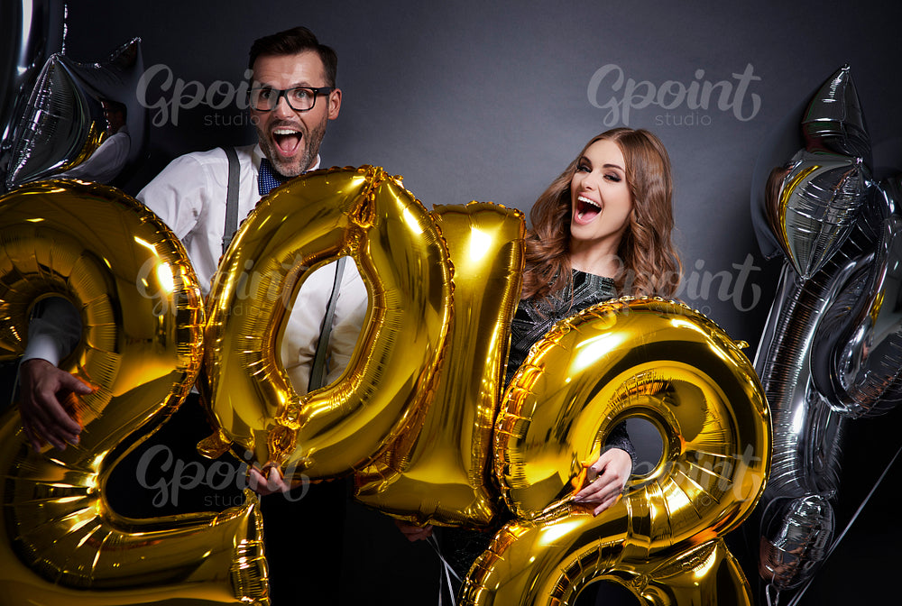 Surprised couple holding new year's balloon
