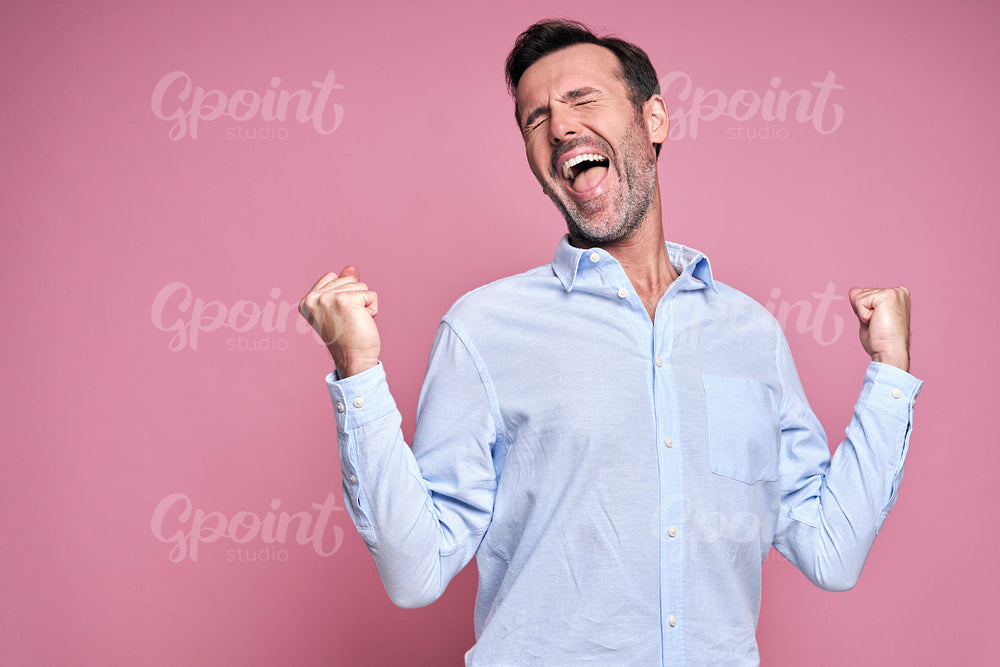 Man on pink background with hand raised 