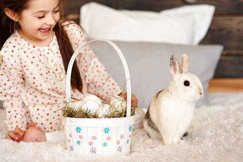 Girl having fun with rabbit in bedroom