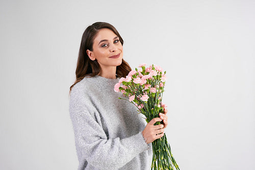 Smiling woman holding bunch of flowers in studio shot