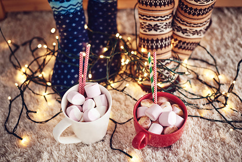Two mugs with hot chocolate and marshmallow on rug