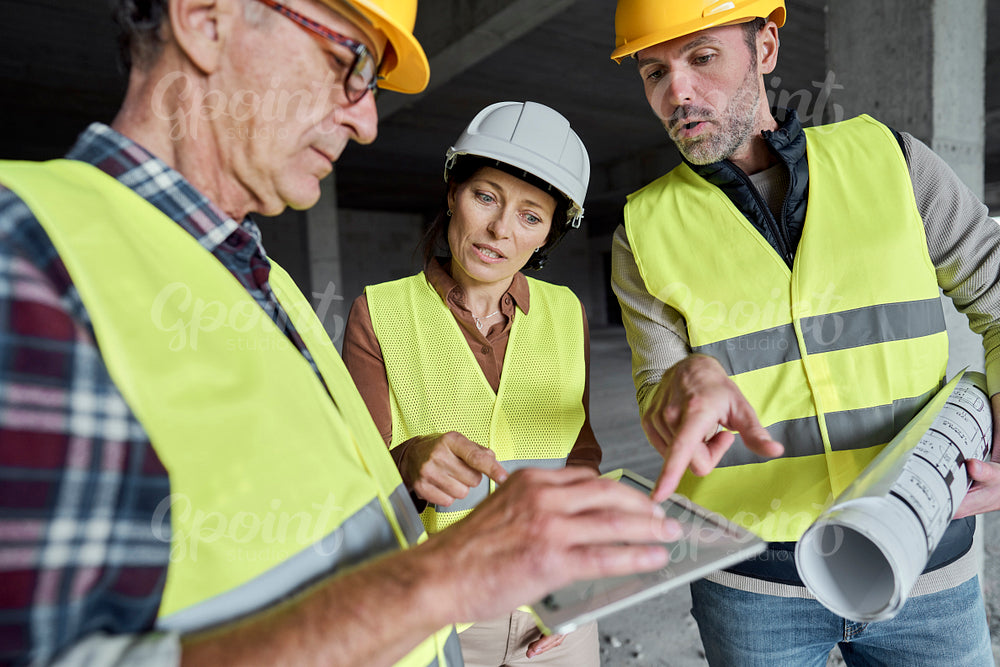 Three caucasian engineers discussing over digital tablet on the construction site