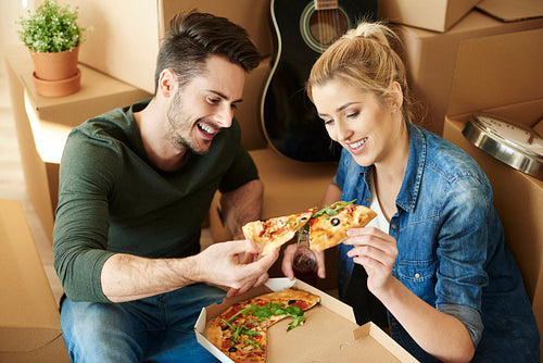 Couple eating pizza next to moving boxes