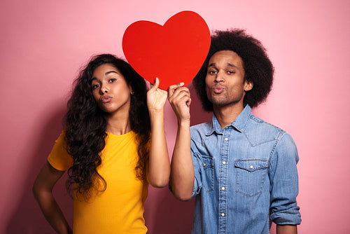 African couple with red heart in studio shot.