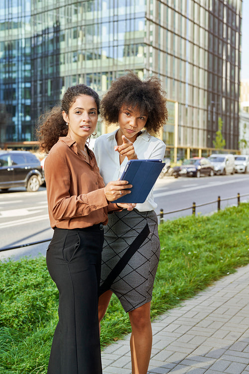 Two businesswomen with digital tablet pointing something in the city