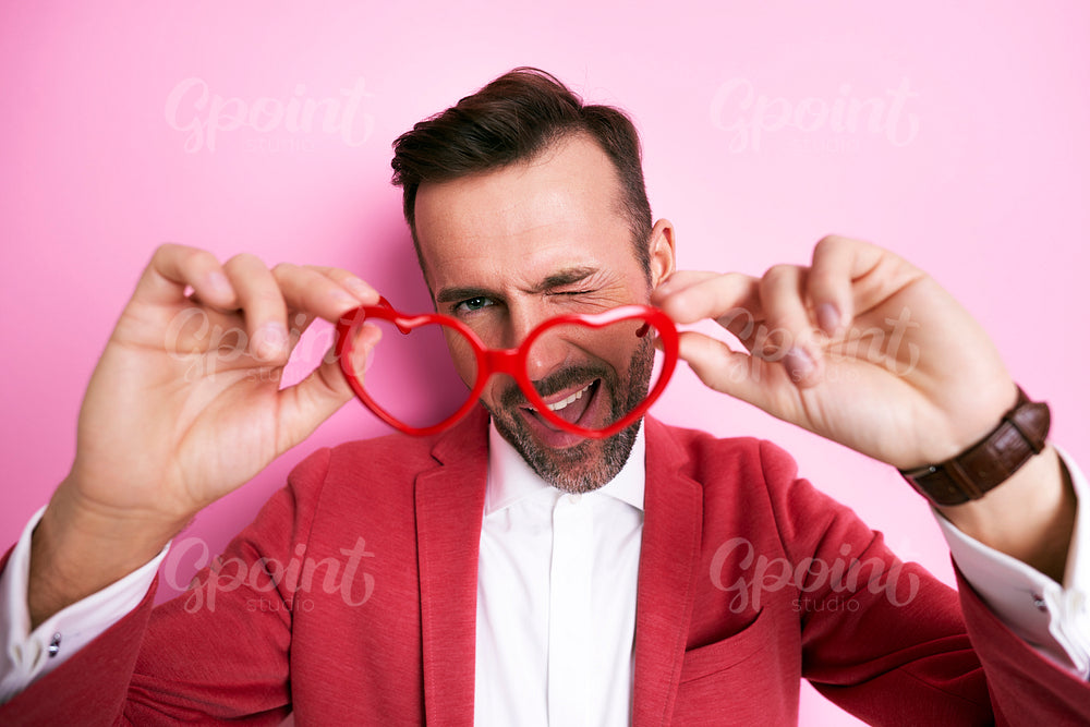 Woman holding eyeglasses in front of face and winking