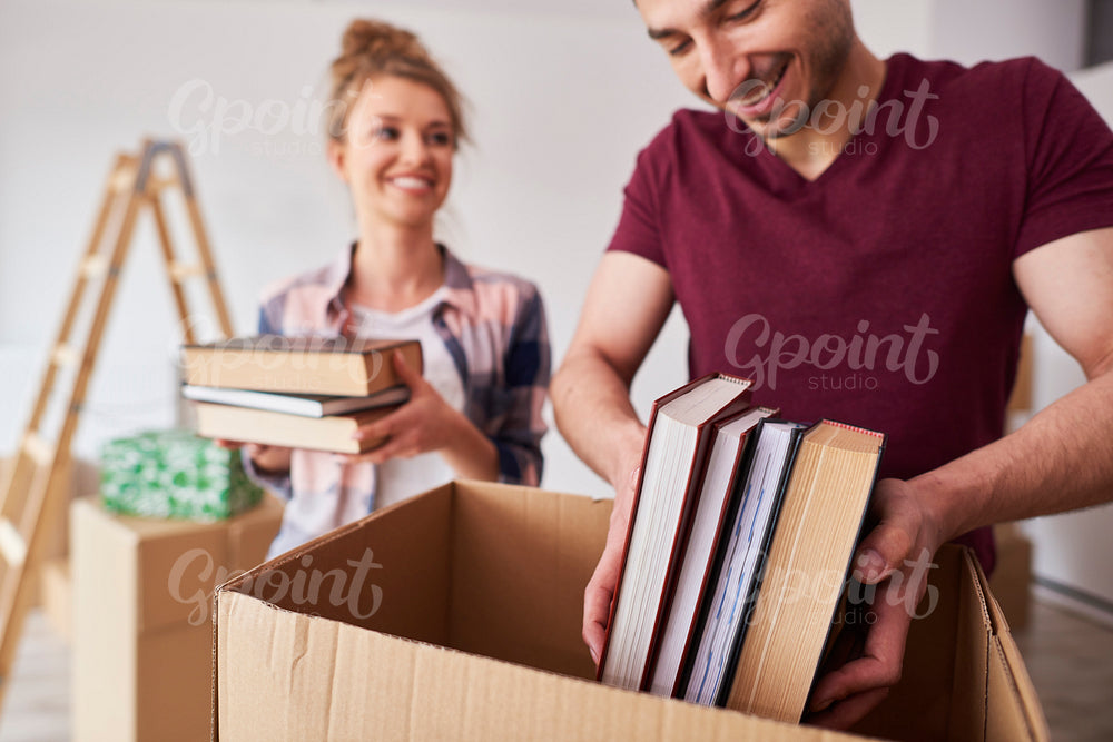 Young couple packing books into box