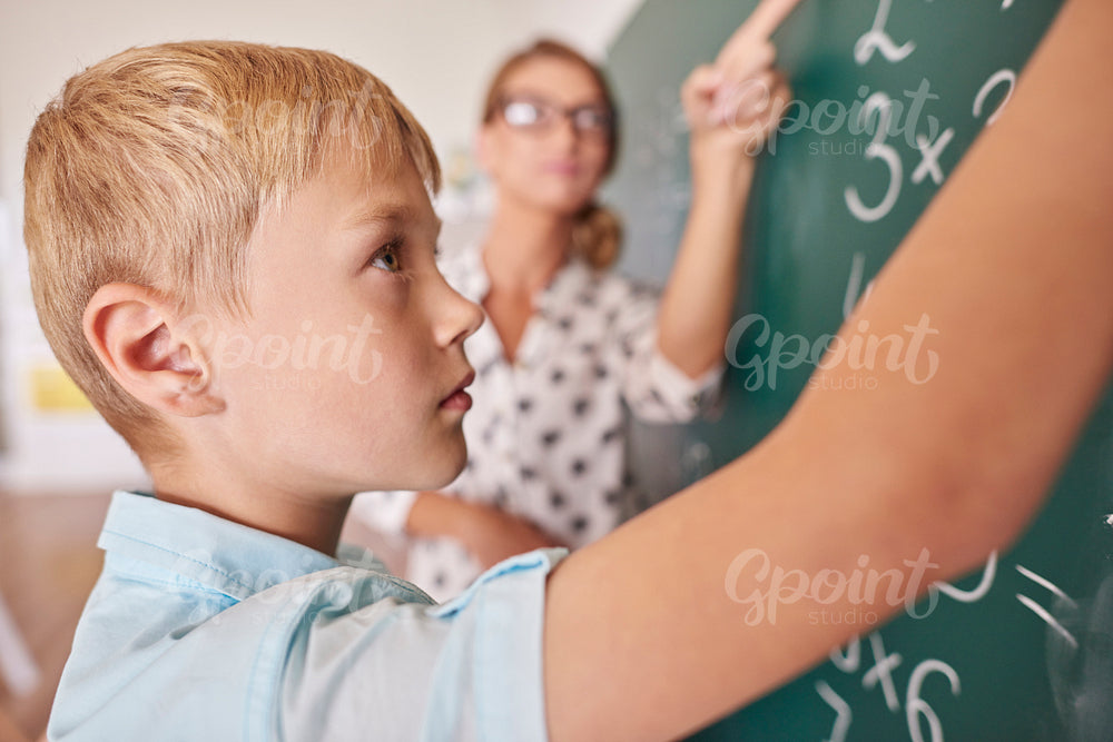 Student boy doing math problem on chalkboard