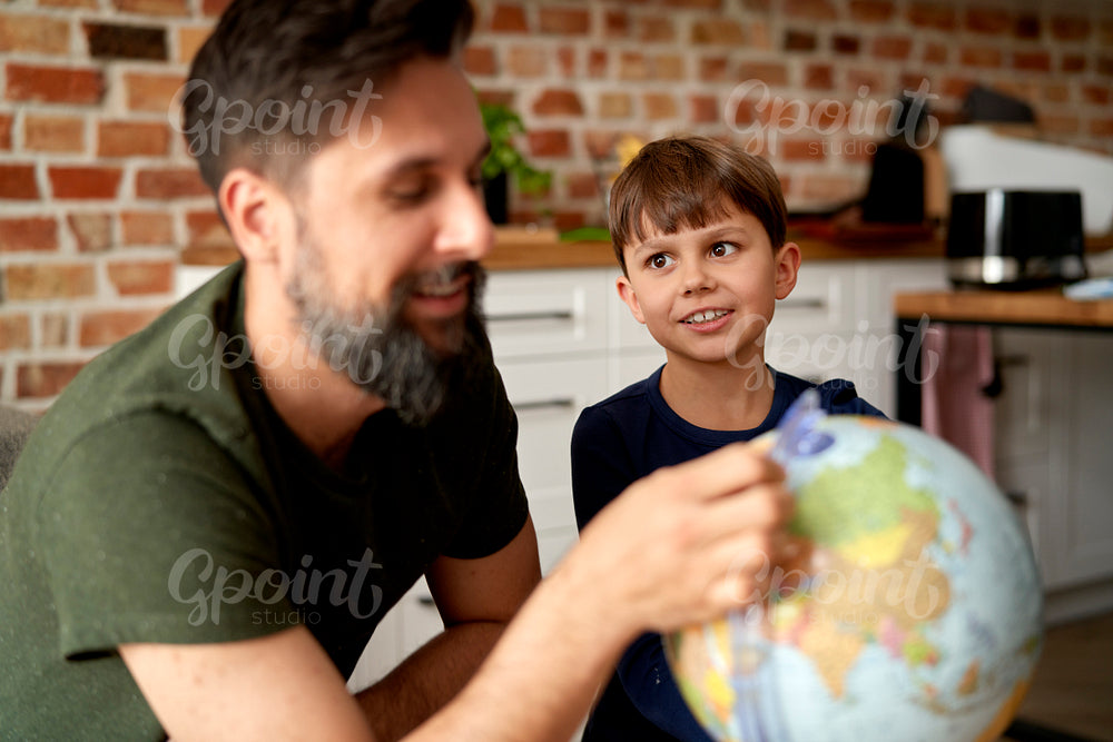 Father and son sitting with globe and planning travel