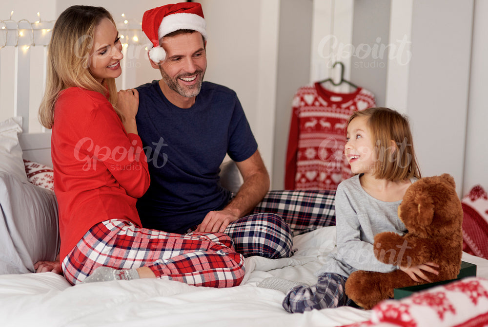 Happy family spending Christmas morning together in the bed