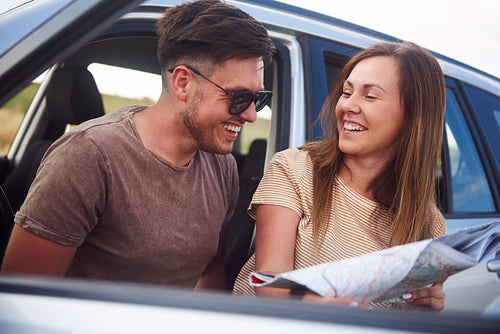 Young couple reading a map during road trip