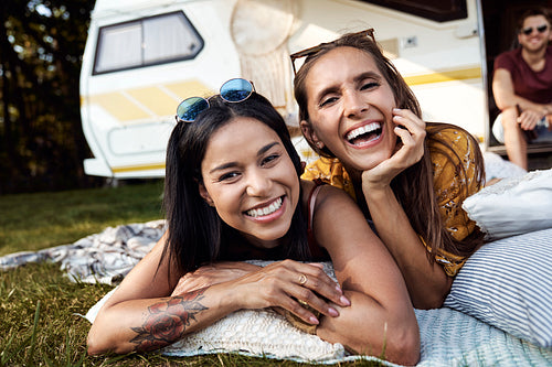 Portrait of young cheerful women friends and camper car in the background
