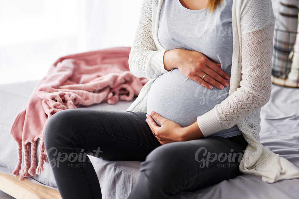 Unrecognizable pregnant woman touching her stomach