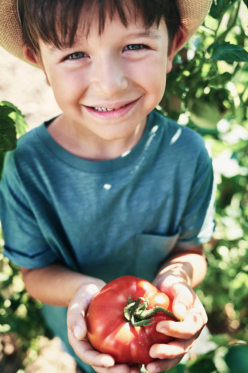 Close up portrait of boy with ripe tomato