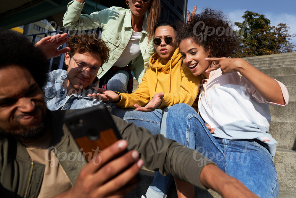 Young people gesturing and doing selfie together outdoors
