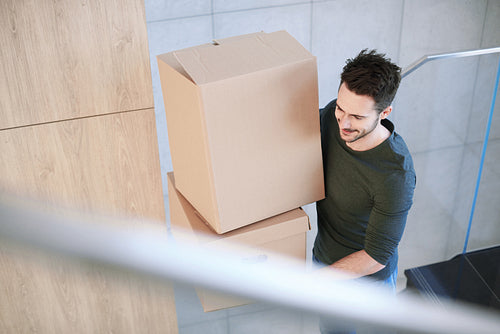 Man smiling and carrying moving box indoors