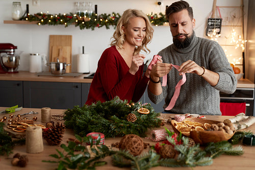 Woman teaching a man to make ribbons for a wreath