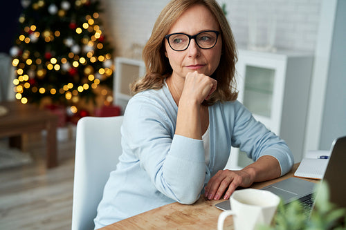 Pensive mature woman sitting alone at Christmas time