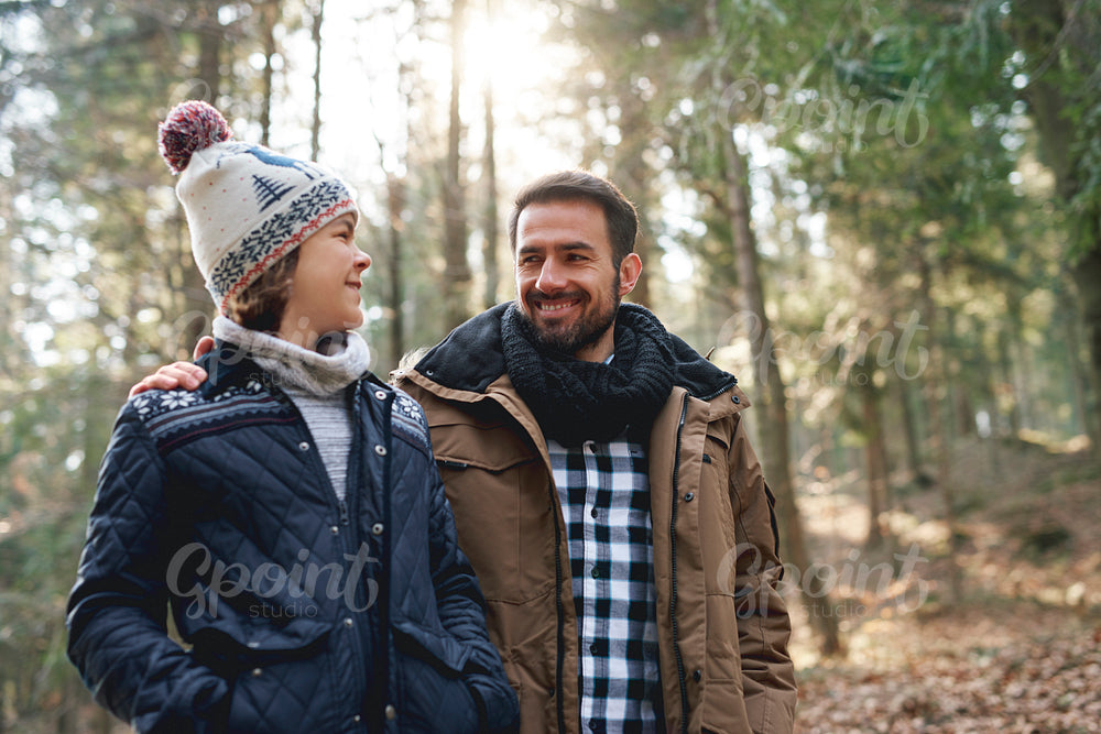 Happy dad and teenage son walking in the autumn forest