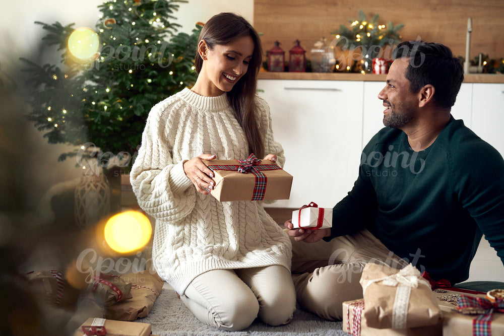 Multi ethnicity couple sharing Christmas present together at home 
