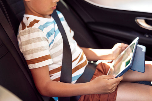Close up of boy with digital tablet in the car