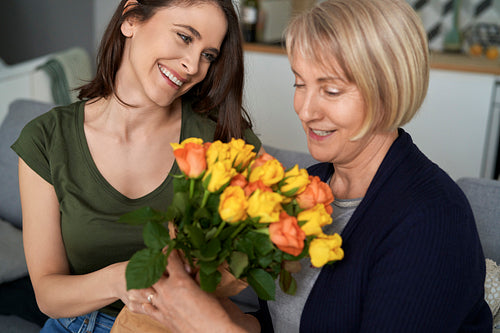 Daughter giving a loving mother a bouquet of flowers