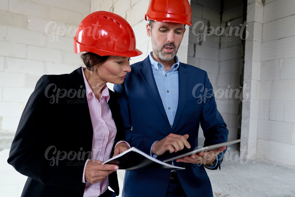 Two caucasian engineers and investors discussing on construction site 
