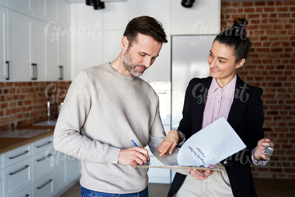 Man with real estate agent signing contract of new apartment