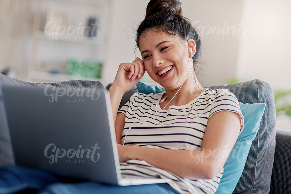 Young Asian woman laughing while watching something on a laptop.