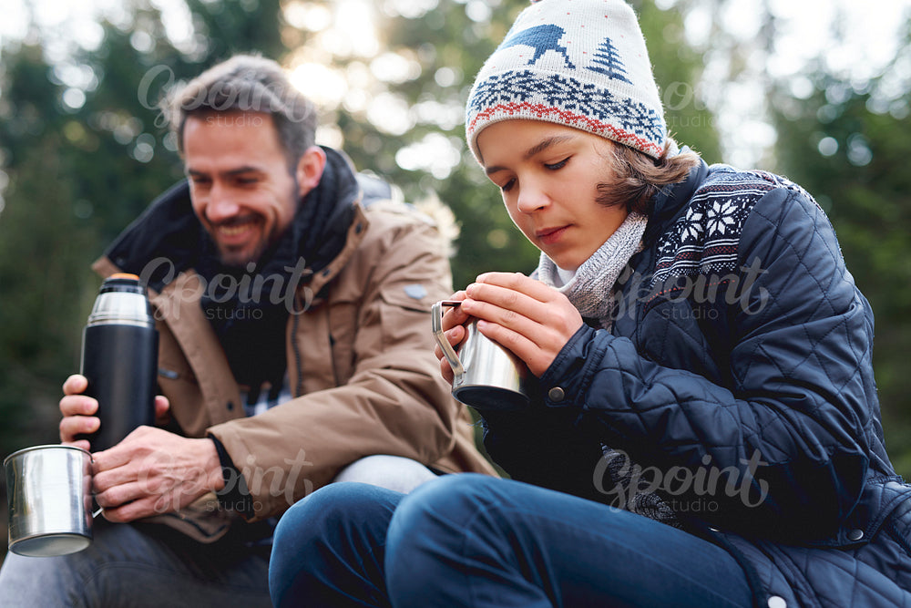 Teenage boy drinking hot tea in autumn forest