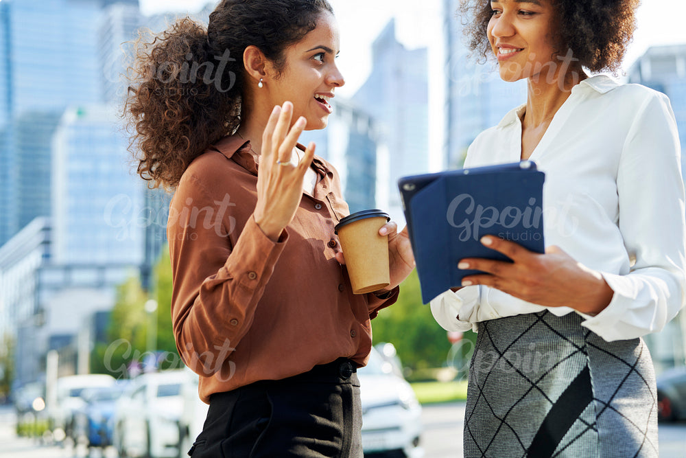 Two businesswomen discussing with digital tablet in the city