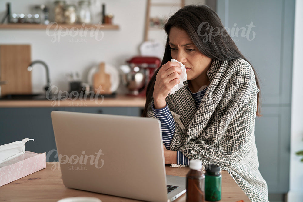 Sick woman in front of laptop at home