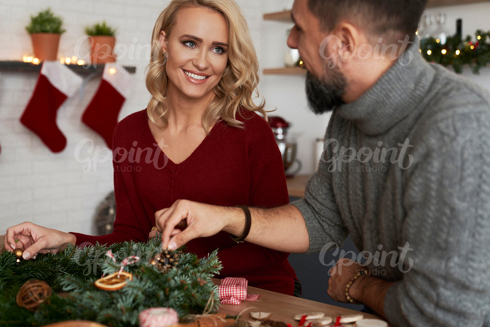 Happy couple decorating a Christmas wreath together
