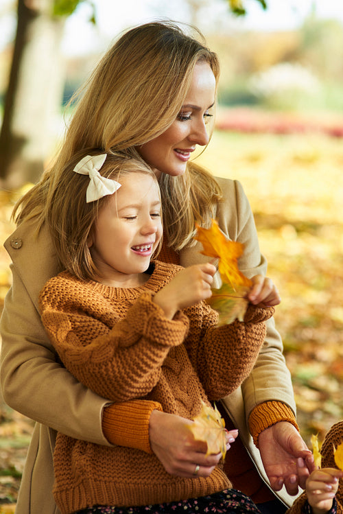 Mother and daughter picking leafs on the fall season