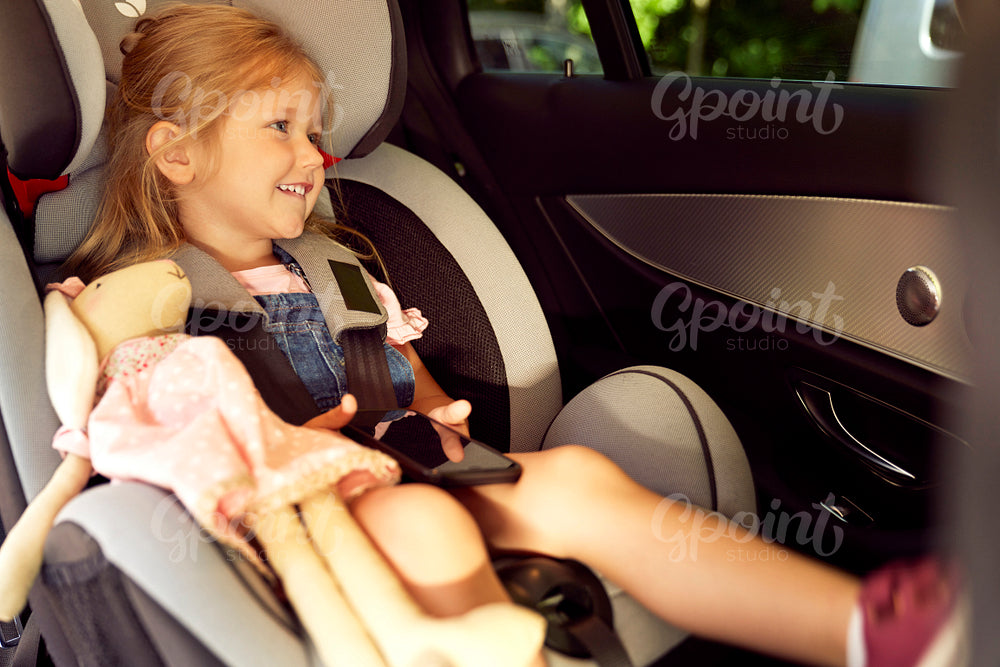 Cute girl sitting in the baby car seat