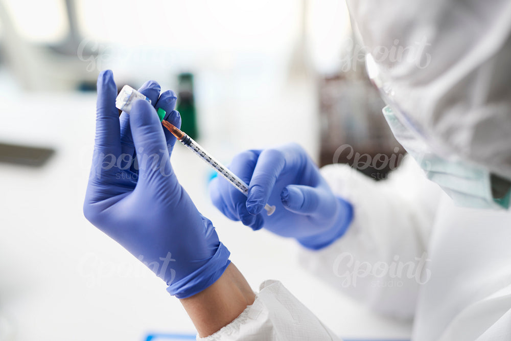 Human hands holding coronavirus medicine and a syringe