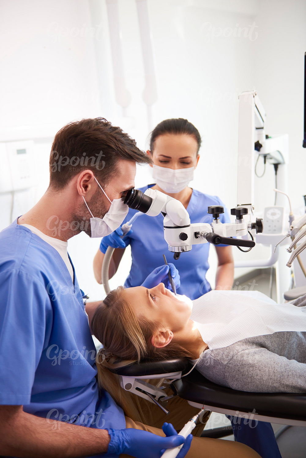 Dentist and his assistant working with dental microscope