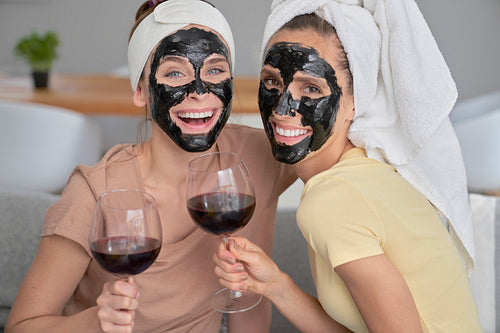 Portrait of two girls with beauty mask and wineglass