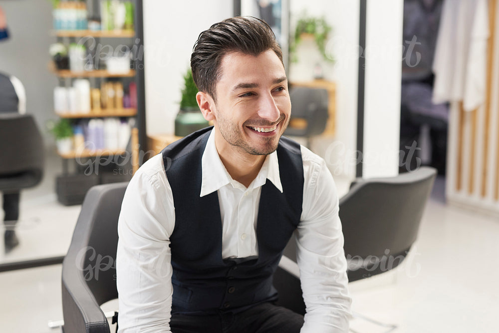 Smiling barber sitting in hair salon