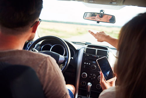 Young couple using a mobile phone during road trip