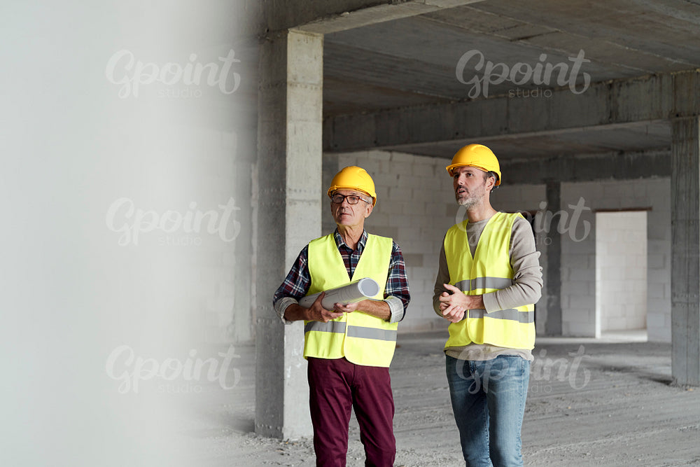 Two mature caucasian engineers discussing on construction site   