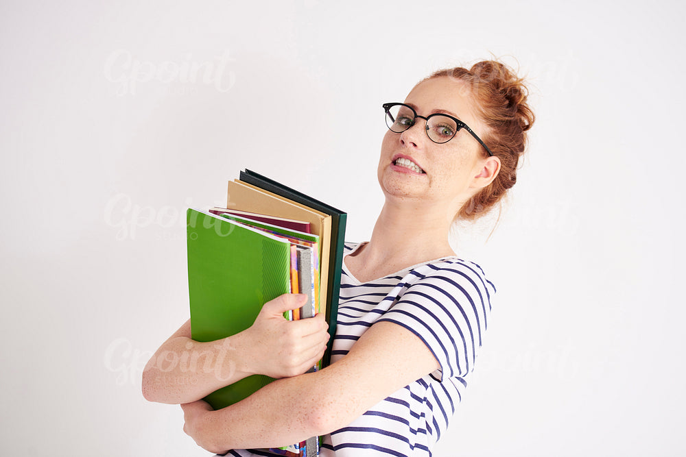 Playful student holding pile of heavy books at studio shot