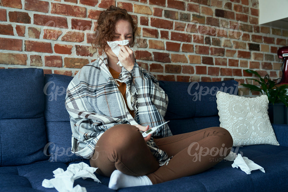Infected caucasian woman blowing nose into tissue at home 