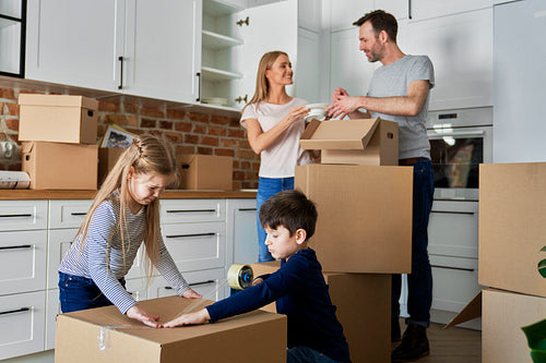 Family packing cardboard boxes for moving house