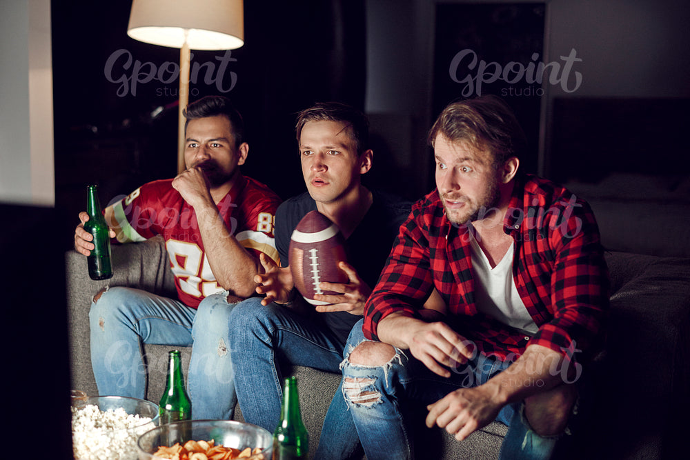 Football fans watching match with beers and snacks
