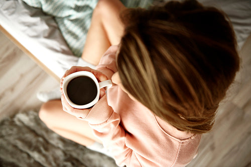 Unrecognizable woman drinking coffee in bed